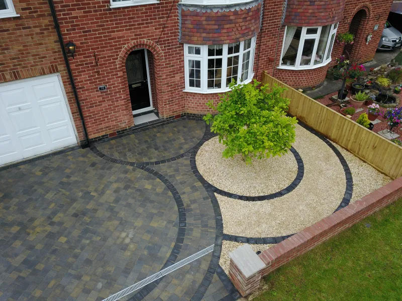 Curved block paved driveway with gravel circle and tree feature