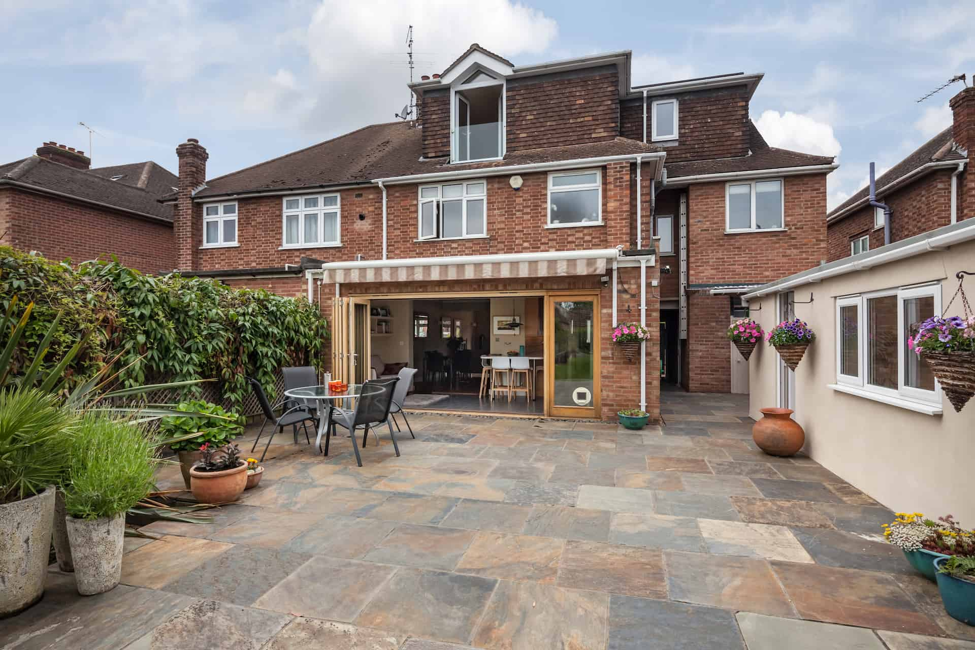 Slate-toned patio terrace to the rear of a brick home with bifold doors
