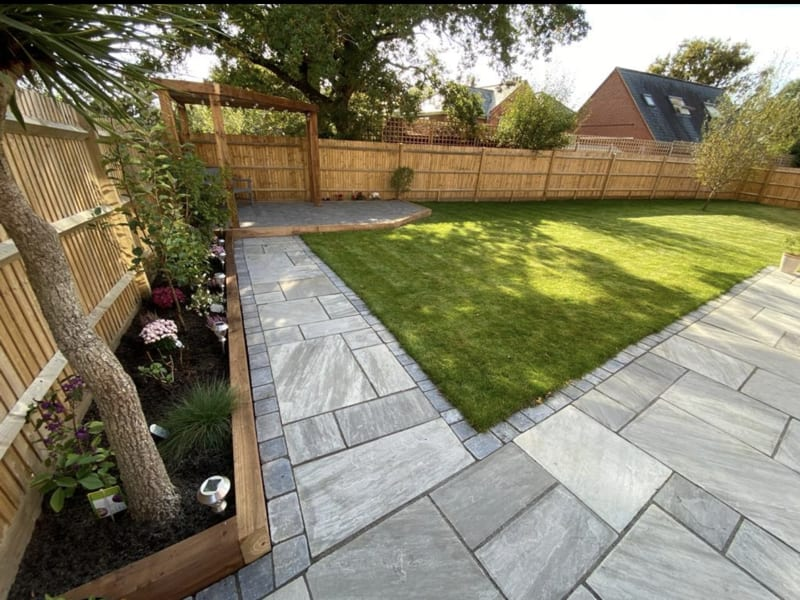 Garden with grey paving path, sleeper borders and pergola seating area